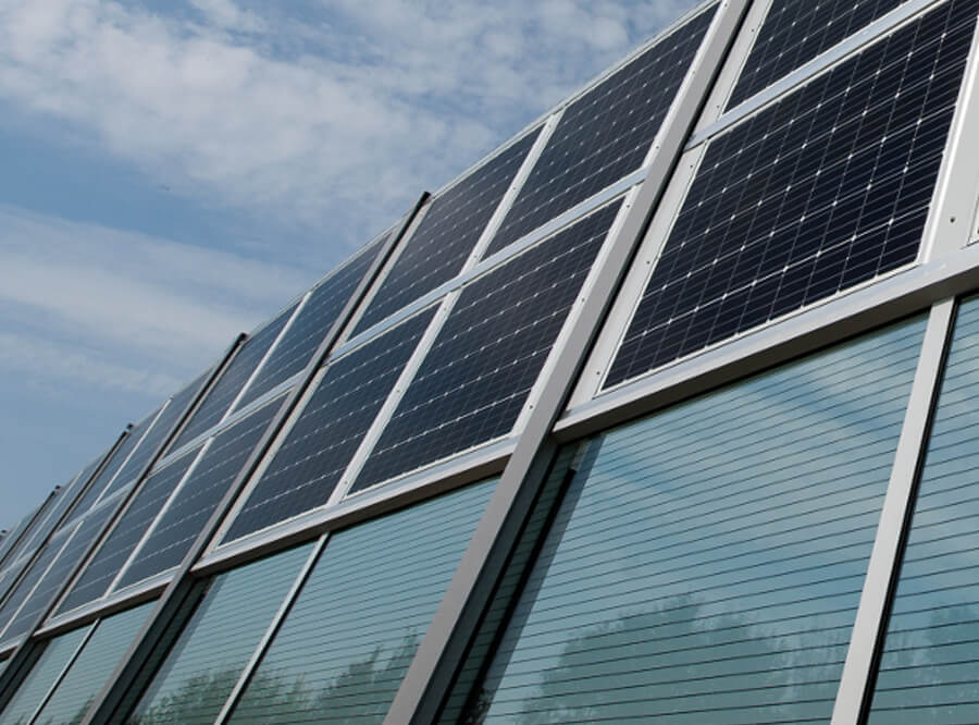 Wir sehen von unten fotografiert eine Lärmschutzwand, die im oberen Teil aus Photovoltaikmodulen besteht.