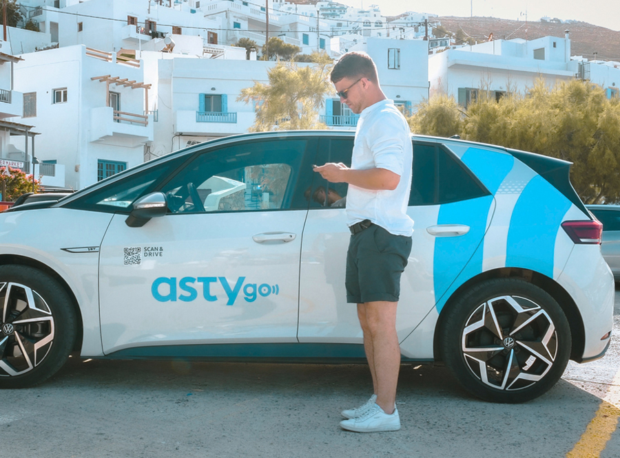 Man standing next to an electric car looking at his smartphone