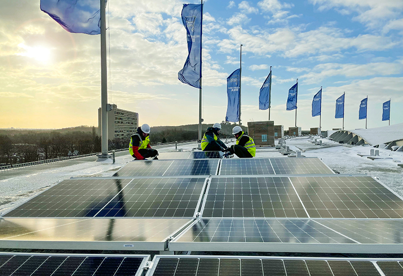 Monteure auf dem Olympiastadion in Berlin bei der Montage von Solarpanelen.